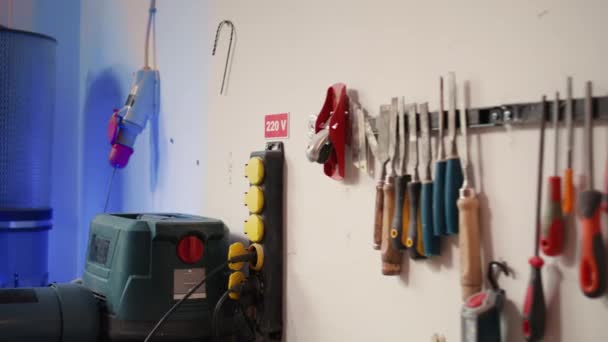 背中の棚の木工用具が付いている家具のアセンブリの店の紡錘のモールダーの電気ルーターの閉鎖 スタジオで木材をサンディングするために使用される手動機器に焦点を当て パンニングショット — ストック動画
