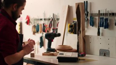 Marangoz ilerideki görev için uygun bir matkap başlığını değiştiriyor, kereste bloğuna delikler açıyor. Montaj atölyesinde görevli iş için elektrikli teçhizat hazırlayan kabin yapımcısı, kamera A