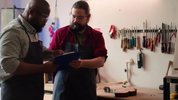 Carpinteiro Usando Óculos Segurança Dando Prancheta Com Plantas Para Assistente — Vídeo de Stock