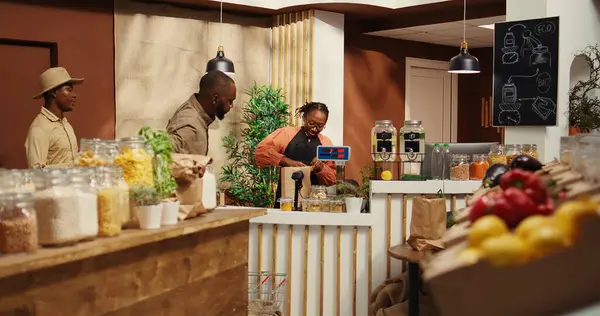 stock image Merchant weighting organic produce for customer at checkout, placing all fresh fruits and veggies on scale at cash register. Woman vendor selling eco friendly nonpolluting merchandise. Camera 2.