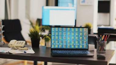 Ticaret stratejileri geliştirmek için toplanan borsa verilerini gösteren dizüstü bilgisayarla boş bir ofiste masa. Şirket iş yerindeki dizüstü bilgisayar ekranındaki eski analizler ticaret platformunu gösteriyor