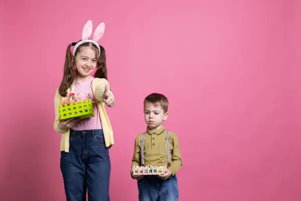 欢天喜地的兄弟姐妹欢欢喜喜地庆祝着复活节和春天的到来 小女孩在镜头前竖起大拇指 兄妹们展示装满彩绘鸡蛋和装饰品的篮子 — 图库照片