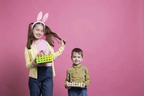 カメラでお祝いの手作りの装飾を提示するポジティブかわいい子供たちは イースターの休日のイベントや春の時間について喜びを感じます 兄と妹は絵の卵でバスケットを見せます — ストック写真