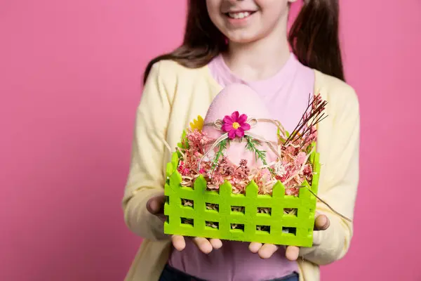 彼女の手作りのイースターのアレンジを提示する陽気な少女は 塗られた卵とかわいい装飾でいっぱいのバスケットを持っています 春のお祭りを祝う小さな子供たち クローズアップ ストック画像