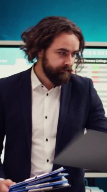 Personel denetleyicisi, bir organizasyon toplantısında performans ile ilgili güncel verileri panolara sunar. Lider, verimlilik ve optimizasyon çabaları konusunda çalışanlarına danışıyor. Kamera B.