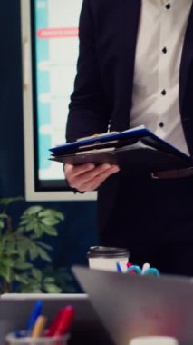 Girişim ekibi yürütme toplantısında stratejik planlar ve finansal tahminler üzerinde tartışıyor, yönetici bilgi grafikli panolar veriyor. Veri raporları ile kaynak tahsisine karar veriliyor. Kamera A.