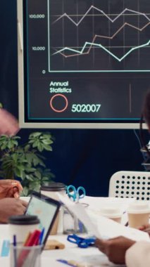 Etkileşimli kuruldaki aylık satış bilgi grafiklerini inceleyen çeşitli meslektaşlar, gelecekteki iyileştirmeler için daha önceki girişimlere ilişkin geri bildirimleri ölçüyor. Yönetim ekibi bir toplantıda olacak. Kamera A.