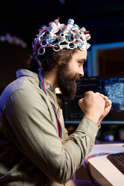 Smiling man with EEG headset on happy after transferring mind into virtual world, becoming one with AI. Cheerful transhumanist celebrating after gaining superintelligence using neuroscientific tech clipart