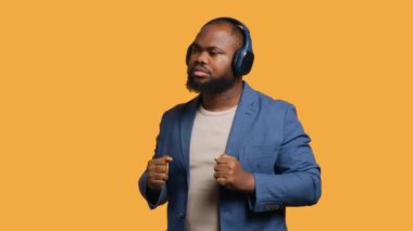 Mutlu Afro-Amerikan vatandaşı, kulaklıkla elektronik şarkılar dinleyip eğleniyor. Neşeli BIPOC DJ gibi davranıyor, dans müziğinden hoşlanıyor, stüdyo geçmişi, kamera A