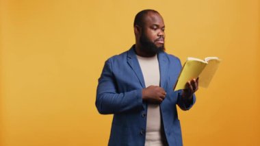 Afrikalı Amerikalı hatip yüksek sesle kitap okuyor, izleyiciler için hikaye anlatıyor. BIPOC çalışanı edebiyat romanı sunuyor, sayfalardan ezber yapıyor, seyircileri eğlendiriyor, stüdyo arka planı, kamera B