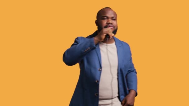 Upbeat 아프리카계 미국인 마이크를 노란색 스튜디오 배경에 노래를 상상력있는 군중에게 — 비디오