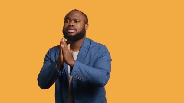 友好的なアフリカ系アメリカ人男性は謝罪のジェスチャーで手を組み 許しを求める 申し訳ないジェスチャーをしている謝罪Bipoc男 スタジオの背景 カメラAに孤立した恩赦を求める — ストック動画