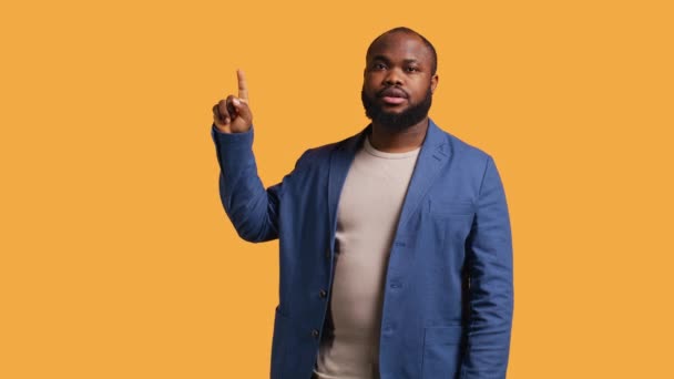 非裔美国广告商用手指向上指点 做推荐 与观众交谈 男人抬起头来 向观众展示一些东西 孤立在工作室的背景之外 — 图库视频影像