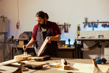 Dolap ustası, hasarı önlemek ve koruma sağlamak için ahşap yüzeye vernik uyguluyor. Marangoz dükkanında marangozluk uzmanı ahşap döşemeyi bitiriyor, yağ kürkleri dikiyor.