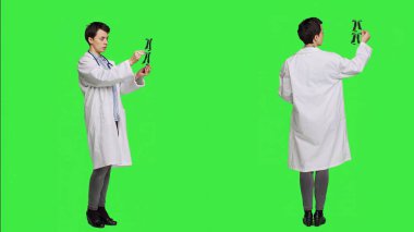 Genel pratisyen hekim yeşil ekran arkaplanı taraması yapıyor. Teşhis için x ışını sonuçlarına bakıyor. Beyaz önlüklü doktor radyoloji bilimi ve araştırma yapıyor. Kamera A.