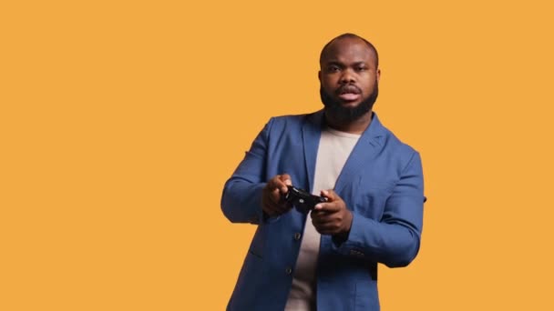陽気なアフリカ系アメリカ人ゲーマーは コントローラーを保持するジェスチャーにサインアップし ビデオゲームをプレイします ゲームをすることに興奮する楽しい人 ハンドジェスチャー スタジオの背景 カメラB ロイヤリティフリーストック映像