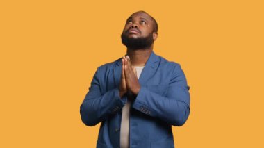 Dindar Afrikalı Amerikalı adam Tanrı 'sına dua edip af diliyor. Ruhani BIPOC adamı el kol hareketi yapıyor, itiraf ediyor, af diliyor, stüdyo arka planında izole edilmiş, kamera A