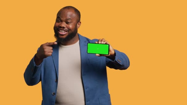 男人用孤立的屏幕电话进行影响者营销的肖像 展示大拇指的标志 工作室背景 快乐的Bipoc人拿着空的复制空间模拟手机 相机A — 图库视频影像