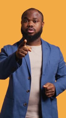 Dikey video hayal kırıklığına uğramış Afrikalı Amerikalı bir adam arkadaşına fiyasko konusunda uyarıda bulunuyor, stüdyo arka planında izole edilmiş. BIPOC çalışanı eşiyle anlaşmazlık içinde, onu suçladı ve ona ders verdi.
