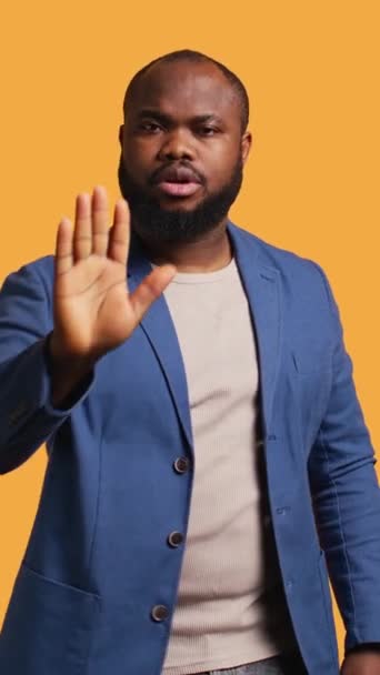 垂直ビデオスターンアフリカ系アメリカ人男性は 停止手のジェスチャーサインを行います スタジオの背景 カメラBに隔離されたコンセプトを終了したい しっかり止めサインジェスチャーをしているBipocの人に通知 — ストック動画