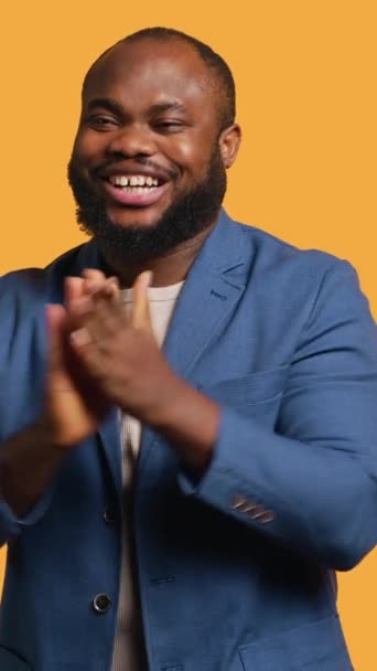 アフリカ系アメリカ人の笑顔を提供する垂直ビデオは 達成に満足して喜んで手を拍手します スタジオの背景 カメラAに隔離されたジェスチャーを賞賛するBipocの人 — ストック動画