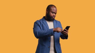Kutlama için cep telefonu tutan neşeli bir adamın portresi havaya yumruk atıp çığlık atıyor. Memnuniyetle Afro-Amerikan vatandaşı cep telefonundan, tezahürattan, stüdyo geçmişinden, B kamerasından iyi haberler okuyor.