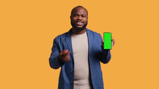 Улыбающийся Африканский Американец Представляет Мобильный Телефон Зеленым Экраном Изолированный Фоне — стоковое видео