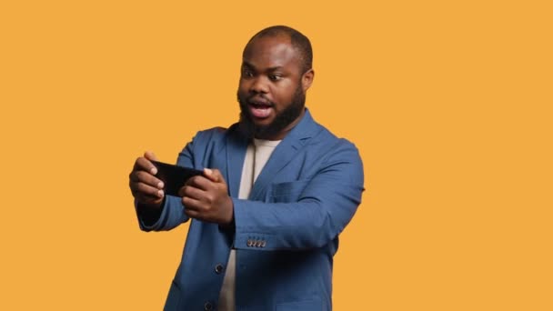 Αφροαμερικάνος Που Παίζει Βιντεοπαιχνίδια Στο Κινητό Του Λειτουργία Τοπίου Απολαμβάνοντας — Αρχείο Βίντεο