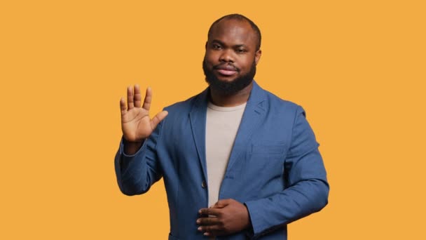 アフリカ系アメリカ人男性は さよならを言って挨拶の手のジェスチャーをすることに消極的だった 悲しいBipocの人物の肖像画は スタジオの背景 カメラAの上に孤立した後に誰かに挨拶するために腕を上げる — ストック動画
