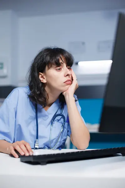 현대적인 클리닉 데스크에서 코카서스 실무자 피곤하지만 간호사 사무실에서 컴퓨터를 검사를 스톡 이미지