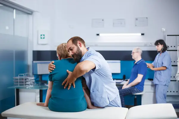 Νοσοκόμα Μπλε Ποδιά Που Θεραπεύει Ηλικιωμένη Γυναίκα Πόνο Στην Πλάτη Φωτογραφία Αρχείου