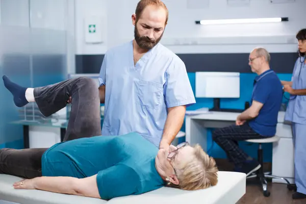 Физиотерапевт Помогающий Пожилой Женщине Болями Мышцах Ног Клинике Остеопатии Хиропрактик Стоковое Изображение
