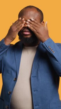 Dikey video Afrikalı Amerikalı adam gözleri, kulakları ve ağzı elleriyle kaplıyor, üç bilge maymunu taklit ediyor. BIPOC çalışanı görmüyor, duymuyor ve jest konseptini konuşmuyor, stüdyo.