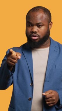 Dikey video hayal kırıklığına uğramış Afrikalı Amerikalı bir adam arkadaşına fiyasko konusunda uyarıda bulunuyor, stüdyo arka planında izole edilmiş. BIPOC çalışanı eşiyle anlaşmazlık içinde, onu suçladı ve ona ders verdi.