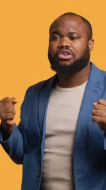 Dikey video Mutlu Afro-Amerikan kişi eğleniyor, ritim içinde dans ediyor, boş zamanların tadını çıkarıyor. Neşeli BIPOC adamı eğlenceli hareketler yaparak eğleniyor, başarısını kutluyor, stüdyo