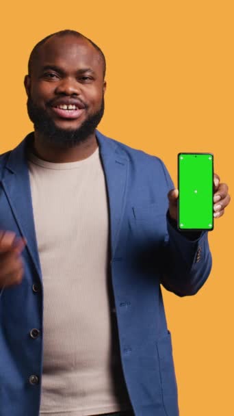 Vertikal Video Leende Afrikansk Amerikansk Man Presenterar Mobiltelefon Med Grön — Stockvideo