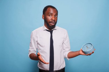Genç işadamı, beyaz gömlek ve siyah kravat takıp çalar saati tutarken zamanın tükenmesine şaşırmış görünüyor. Afrika kökenli Amerikalı bir ofis çalışanı toplantıya geç kaldığı için panikledi..