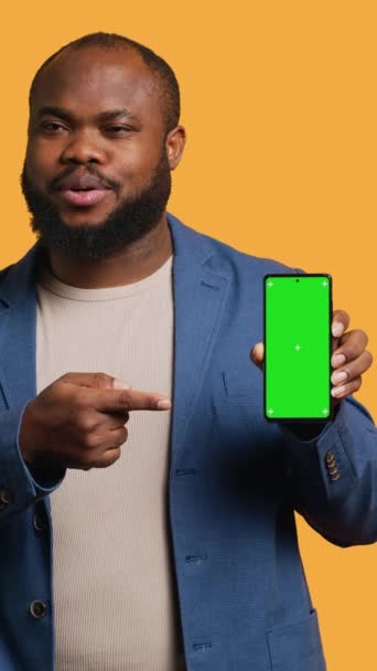 Вертикальное Видео Улыбающийся Африканский Американец Представляет Мобильный Телефон Зеленым Дисплеем — стоковое видео