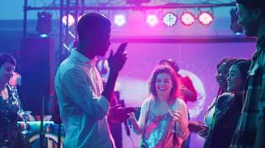 Kulüpte dans figürleri gösteren sıradan bir adam, elektronik müziğe devam eden ve arkadaşlarıyla eğlenen. Bir grup modern insan müzik istasyonunda DJ ile parti yapıyor, dans pisti tıka basa dolu. Üçayak atışı.