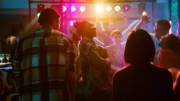 快乐的朋友们在时髦的音乐上跳舞 与Dj一起在舞台上和聚光灯下聚会 一群多样化的人在舞池里跳着舞 在俱乐部的活动中玩得很开心 手持射击 免版税图库图片