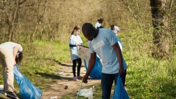 非裔美国人志愿用钳子收集垃圾和塑料垃圾 抓取垃圾 并在垃圾处理中回收利用 积极与森林污染和非法倾倒作斗争 相机A — 图库视频影像