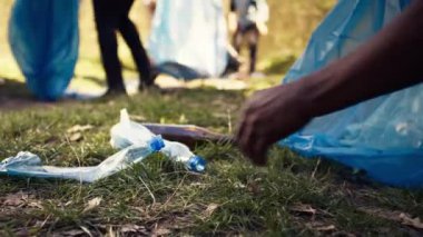 İnsanlar doğal çevrenin temizliğini ormandaki çöp ve geri dönüşümlü nesneleri toplayarak ve çöp torbasında toplayarak destekliyor. Çöpleri toplamak için çatal bıçak kullanmak. Kapatın. Kamera B.