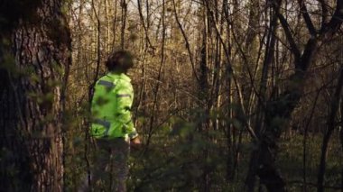 Kurtarma ekibi lideri, kayıp kişiyi bulmak için arama operasyonu sırasında kanıt toplamak için ormanın içinden yol gösteriyor. Bireylerin adını haykıran sivil, bir ormanda kayboldu. Kamera B.