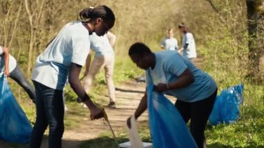 Afrika kökenli Amerikalı gönüllülerden oluşan bir ekip çöpleri yerden topluyor, çöp topluyor ve torbalarda geri dönüşüm yapıyor. Ormanı plastik atıklardan temizleyen kadınlar, yasadışı çöplük. Kamera A.