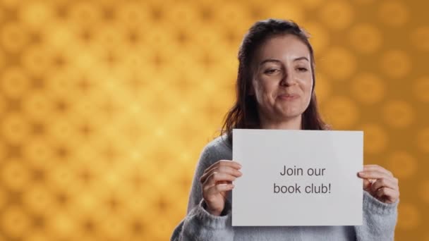 愉快的图书俱乐部主席带着敦促人们加入他们的信息 谈论讲座的重要性 工作室背景 微笑的女人邀请书虫加入她的协会 相机A — 图库视频影像