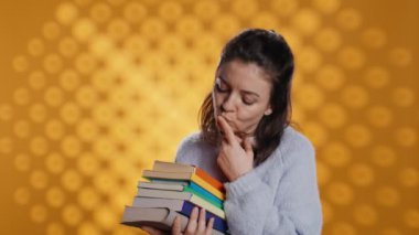 Heyecanlı bir kadın satın alınmış kitap yığınını karıştırıyor, ne okuyacağını seçiyor. Hevesli kitap düşkünü insan boş zamanlarını geçirmek için kitap yığınına bakıyor. Stüdyo arka planı, kamera B...