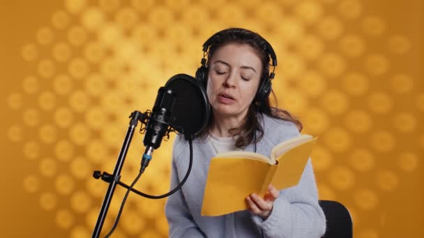 Narrator Noszący Słuchawki Czytający Głos Książki Mikrofonu Żółtym Tle Upbeat — Wideo stockowe