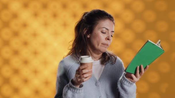 Втомлена Жінка Читає Книгу Тримає Чашку Кави Ізольована Студійному Фоні — стокове відео