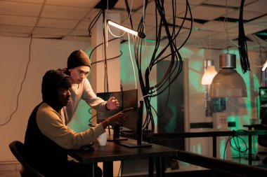 Truva virüsünü kullanarak kötü amaçlı yazılım oluşturan çeşitli ajanlar geceleri güvenlik duvarı şifresini kırmak için birlikte çalışıyorlar. Erkek hackerlar kişisel hassas bilgileri çalmak için veritabanını inceliyor..