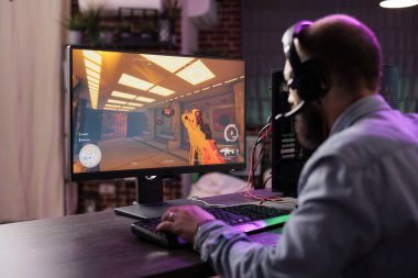 Oyuncu, esport turnuvalarında dikkat dağıtmamak için profesyonel seviyedeki oyun sistemini kullanıyor. Tuğla duvar dairesinde rahatlayan bir adam gecenin geç saatlerinde video oyunu oynuyor.